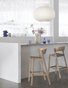 two wooden stools sitting in front of a counter with vases and flowers on it