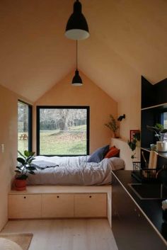 a bed sitting under a window in a bedroom next to a desk and shelves on the wall