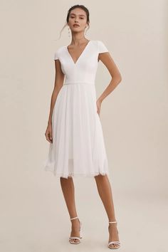 a woman wearing a white dress and heels