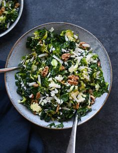 a bowl filled with greens and nuts on top of a blue table cloth next to two bowls