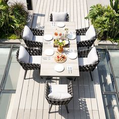 an outdoor dining table with chairs and plates on it