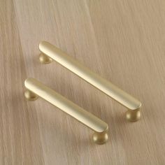 two brass handles on a wooden surface, one is turned to look like the other