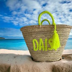 a woven basket with the word dad written on it sitting in front of an ocean