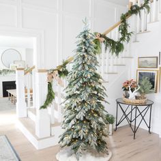 a decorated christmas tree sitting on top of a hard wood floor next to a banister