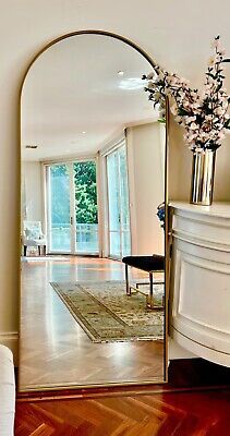 a large mirror sitting on top of a wooden floor next to a white couch and table