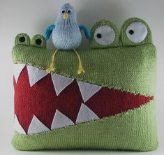 a green pillow with two eyes and a bird sitting on it's back side