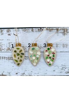 three ceramic hearts hanging from clothes pins on a white wooden background with measurements for each ornament