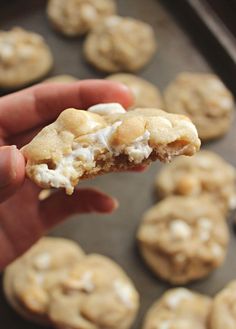 a hand holding a half eaten cookie with marshmallows