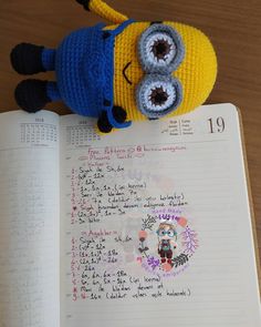 a crocheted minion sitting on top of an open notebook with numbers written in it