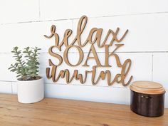 a wooden sign that says relax soak unwind next to a potted plant