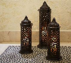 three decorative lanterns sitting on top of a tile floor