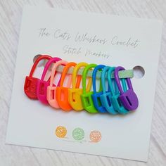 the colorful hair clips have been placed on top of a white card that says, the cat warrior crochet stitch hanger