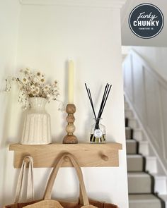 A neutral wall features an oak picture shelf. On the shelf, there is a white vase of flowers, a tall wooden candlestick, and a diffuser. Below the shelf, there are three pegs with two bags hanging from them. Picture Shelves, Hallway Storage, Hallway Furniture, Wood Console Table, Door Color, Hallway Decorating, Solid Wood Furniture