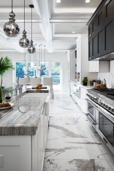 a large kitchen with marble counter tops and white cabinets, along with an island in the middle