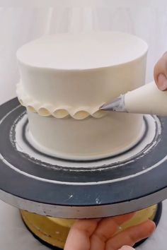 a person is decorating a white cake with icing on the top and bottom