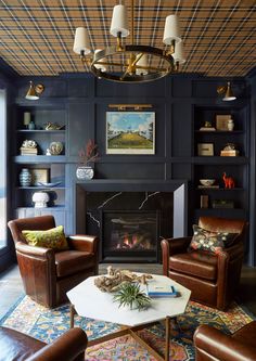 a living room with two leather chairs and a fire place in the middle of it