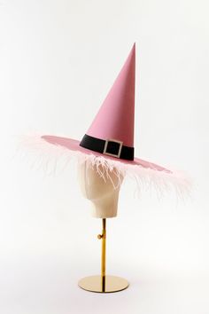 a pink and black hat on a mannequin's head with feathers around it