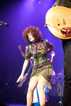 a woman standing on top of a stage next to a guitar