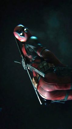 a deadpool character laying on top of a chair in the dark with his eyes open