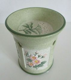 a green vase with flowers painted on it