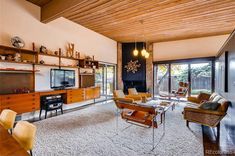 a living room filled with furniture and a flat screen tv on top of a wooden shelf