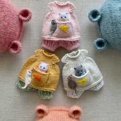 four knitted sweaters with animals in them on a white tablecloth next to each other