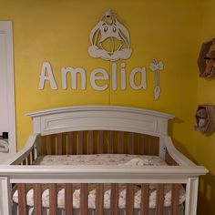 a baby crib in front of a yellow wall with the name amelie on it