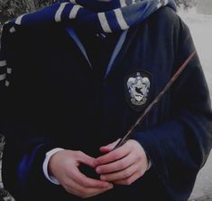 a young boy wearing a harry potter outfit and holding a wand in his hands while standing next to a tree