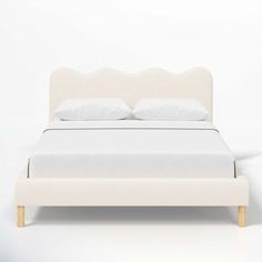 a bed with white sheets and pillows on top of it, against a white wall