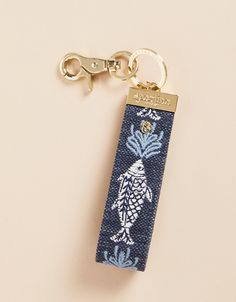 a keychain with a blue and white design on it, hanging from a gold - plated metal hook