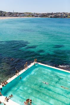 people are swimming in an empty pool near the ocean