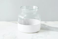 a glass jar with white paper in it sitting on a marble countertop next to a gray wall