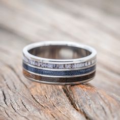 a close up of a wedding ring on top of a piece of wood with blue and white stripes