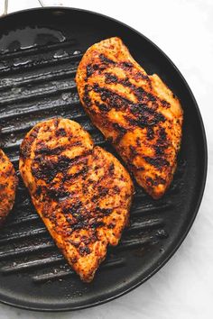 three pieces of chicken cooking on a grill