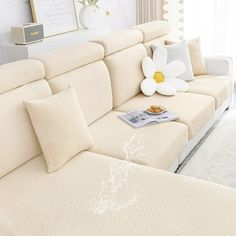 a living room with a white couch and large flower on the corner table next to it