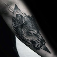 a man's arm with a black and grey tattoo on it, featuring an image of a wolf