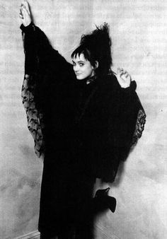 black and white photograph of a woman dressed in an old fashion costume with her arms outstretched