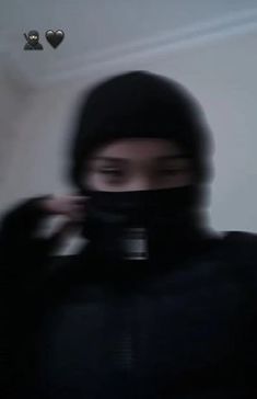 a blurry image of a person wearing a black hoodie and holding a camera