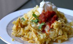 a white plate topped with an egg casserole covered in sauce and sour cream