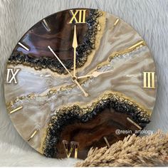 a clock that is on the side of a white furnishing area with gold numbers and roman numerals