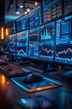 multiple computer monitors and keyboards on a desk in a dark room with neon lights around them