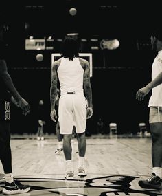 a group of men standing on top of a basketball court with one man in the middle