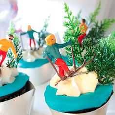 three cupcakes decorated with miniature people and trees