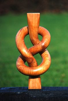 a wooden sculpture sitting on top of a lush green field