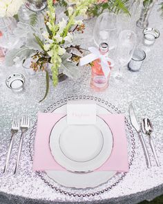 the table is set with silverware and pink napkins