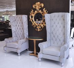 two chairs and a table with a mirror on it in a room filled with furniture