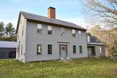 a large gray house sitting on top of a lush green field