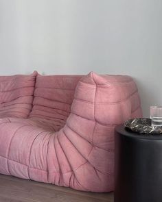 a pink couch sitting on top of a hard wood floor next to a black table