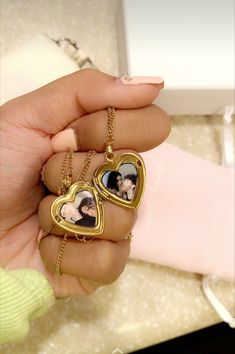 a woman holding two heart shaped pendants in her hand with the photo on it