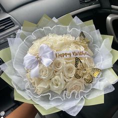 a bouquet of white roses and butterflies in the front seat of a car with happy birthday written on it